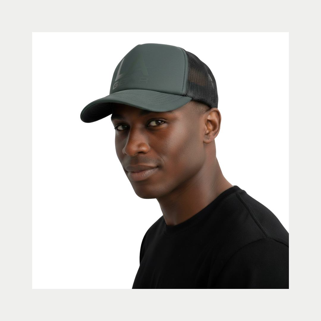 Man wearing a sage trucker hat with a LA Gear logo on a white background.