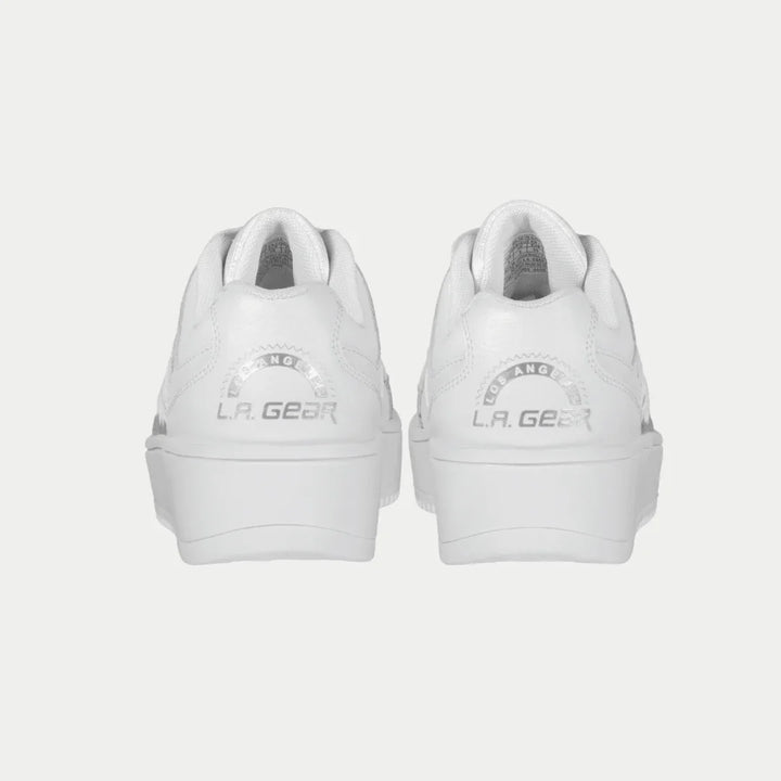 White lowtop sneakers with 'LA Gear' branding on a light gray background