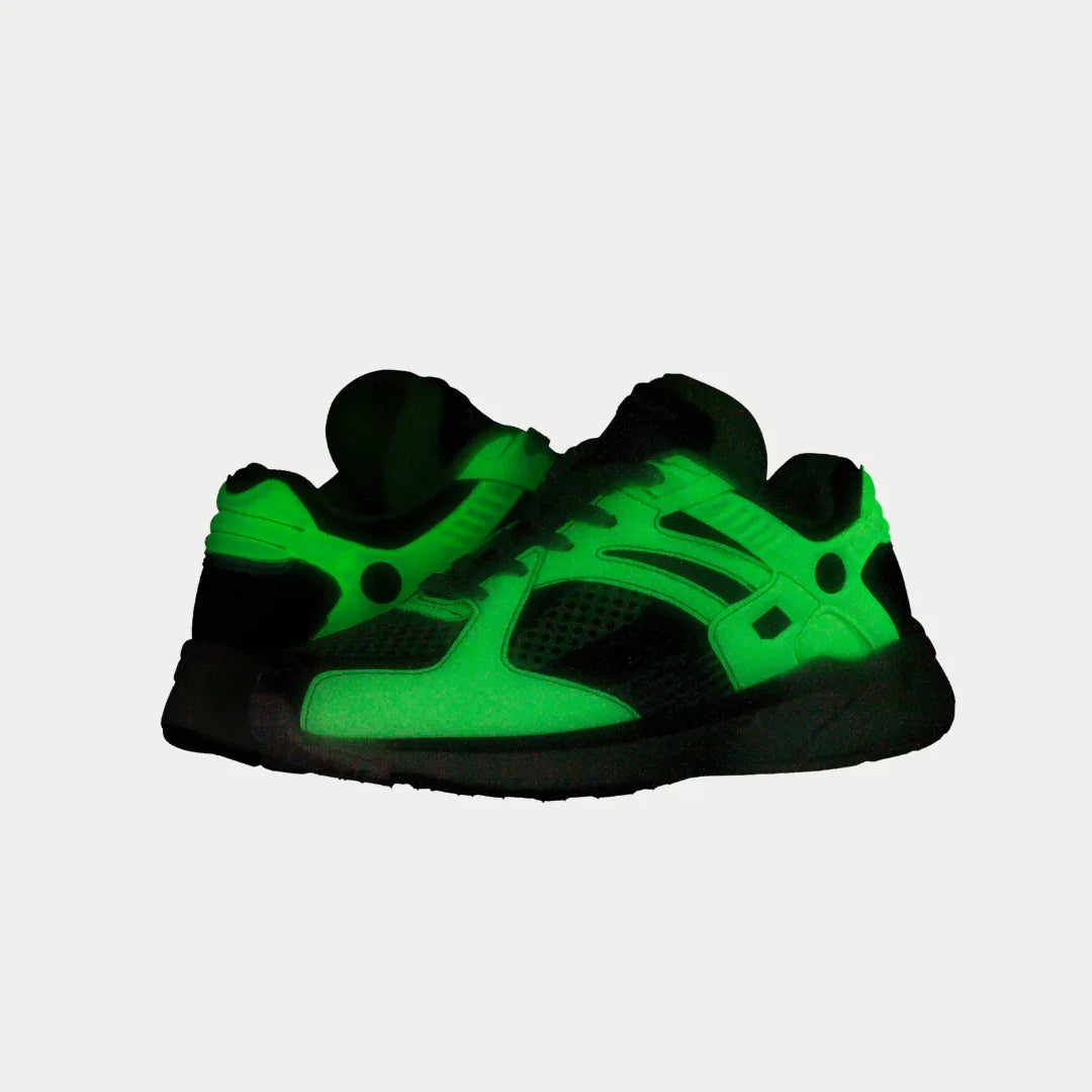 Neon yellow and black lowtop shoes that glow-in-the-dark on a white background